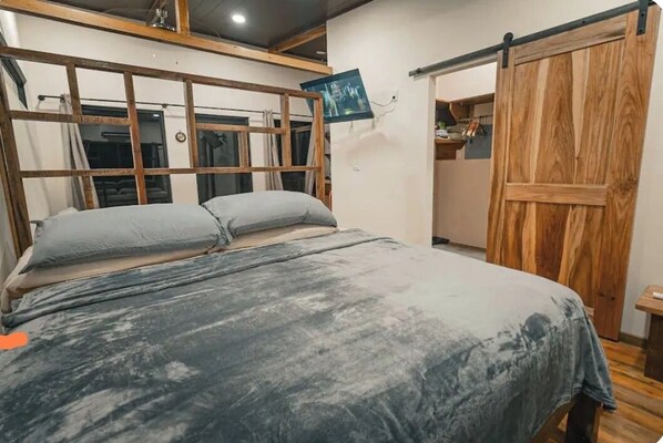 A bedroom with a bed, wooden headboard, and a sliding wooden door.