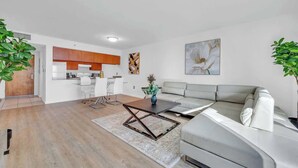 Un salon moderne comprenant un canapé, une table basse et un coin repas avec des chaises.