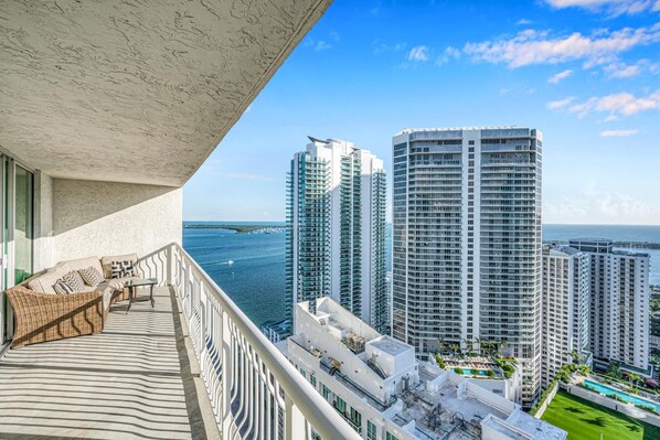 Un balcon offrant une vue sur des immeubles de grande hauteur et sur une étendue d’eau.