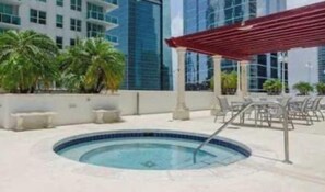 A swimming pool with a red pergola, palm trees, and a modern building in the background.
