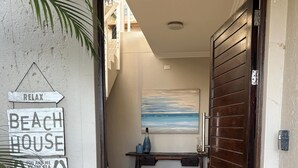 Ein Durchgang zu einem Raum mit einer Holztür, einem Blumentopf und einem Schild, auf dem 'BEACH HOUSE' steht.
