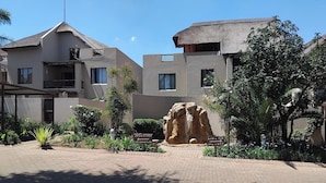 A residential area with modern houses, a paved driveway, and a large rock sculpture.