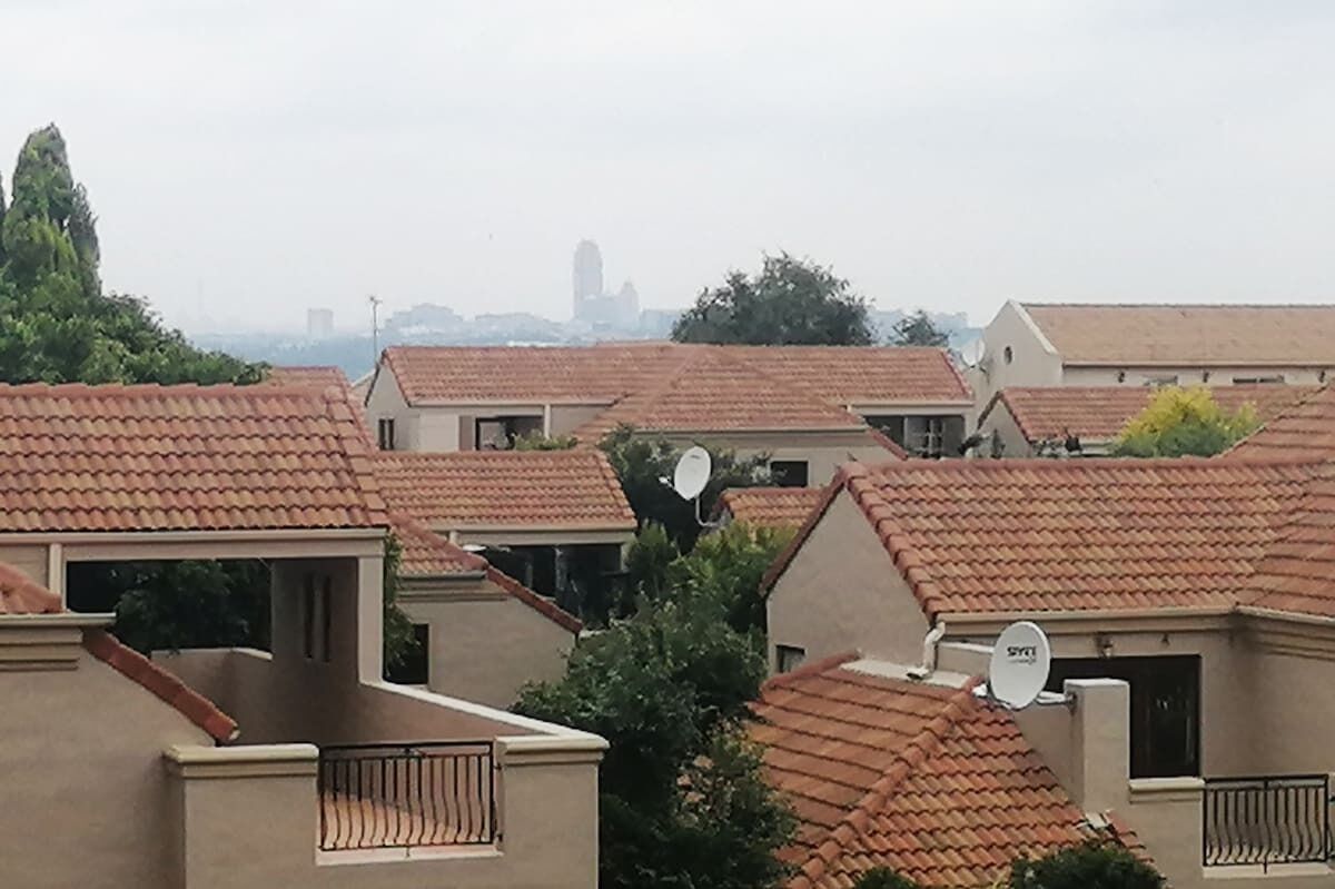 A residential area with houses featuring red-tiled roofs and satellite dishes.