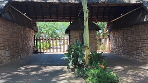 A stone building with a thatched roof, a gated entrance, and a small tree in the center.