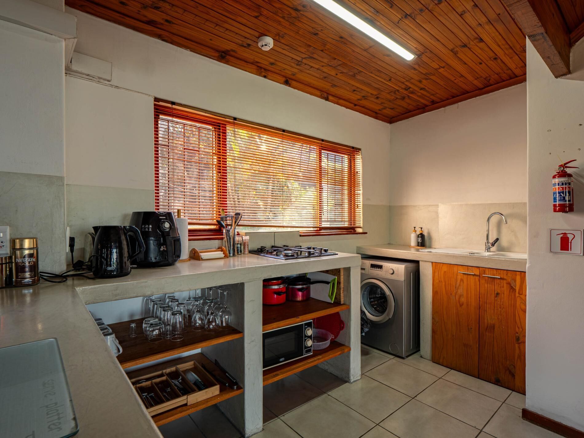 A compact kitchen with a built-in oven, a washing machine, and a sink.