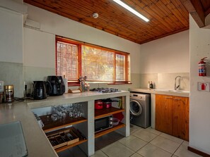 A compact kitchen with a built-in oven, a washing machine, and a sink.