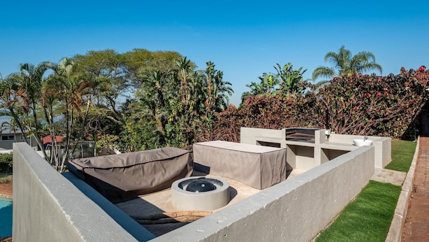 A rooftop patio with a concrete fire pit, seating, and a pool in the background. - Sea Vista - Awesome Sea Views (uMhlanga)