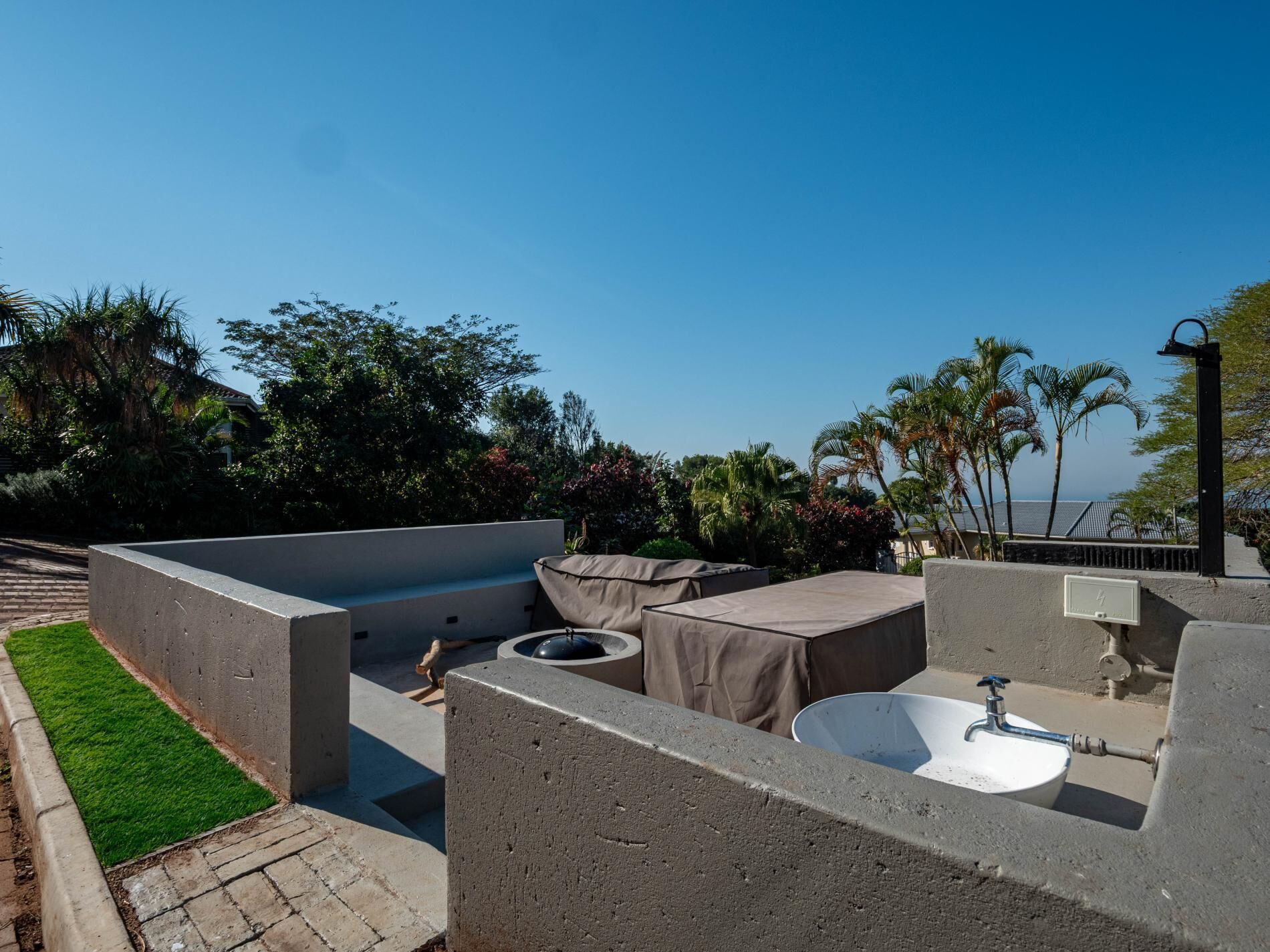 An outdoor patio with a concrete sink, seating area, and a view of the surrounding landscape.