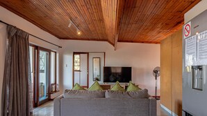 A living room with a wooden ceiling, a grey sofa with cushions, a flat-screen TV, and a wall-mounted Samsung refrigerator. - Sea Vista - Awesome Sea Views (uMhlanga)