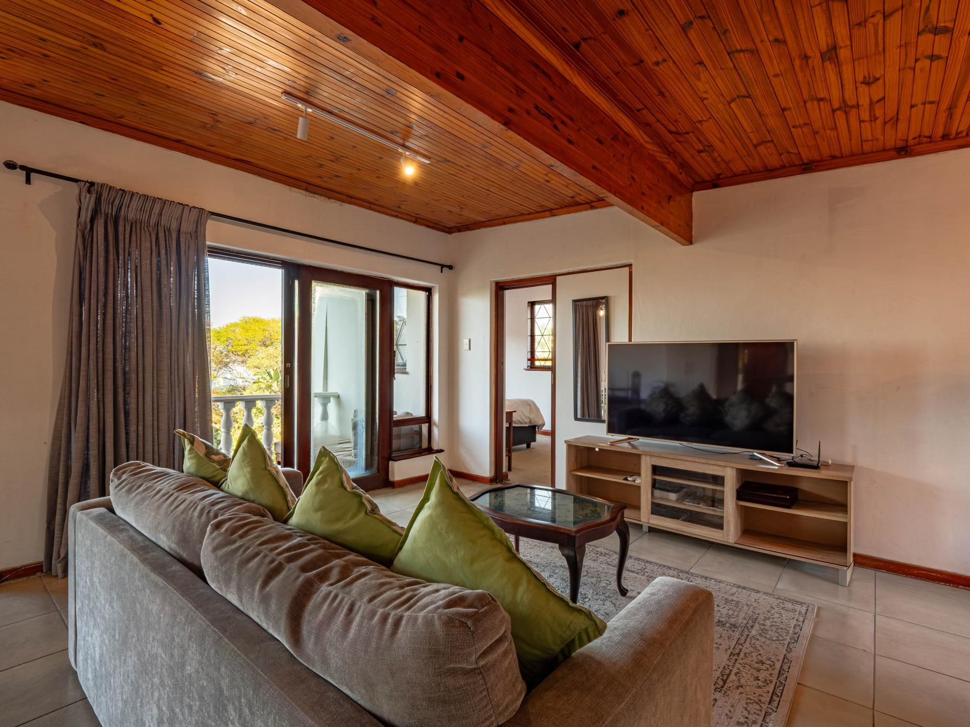 Un salon avec un canapé, un téléviseur et un plafond en bois.