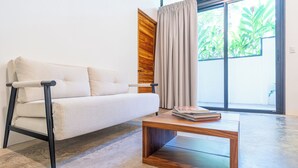 En moderne stue med sofa, sofabord i træ og en skydedør til en altan.