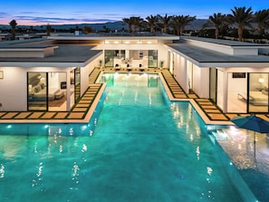 A modern house with a swimming pool, large windows, and a view of palm trees. - The Bravo Villas by AvantStay (Indio)