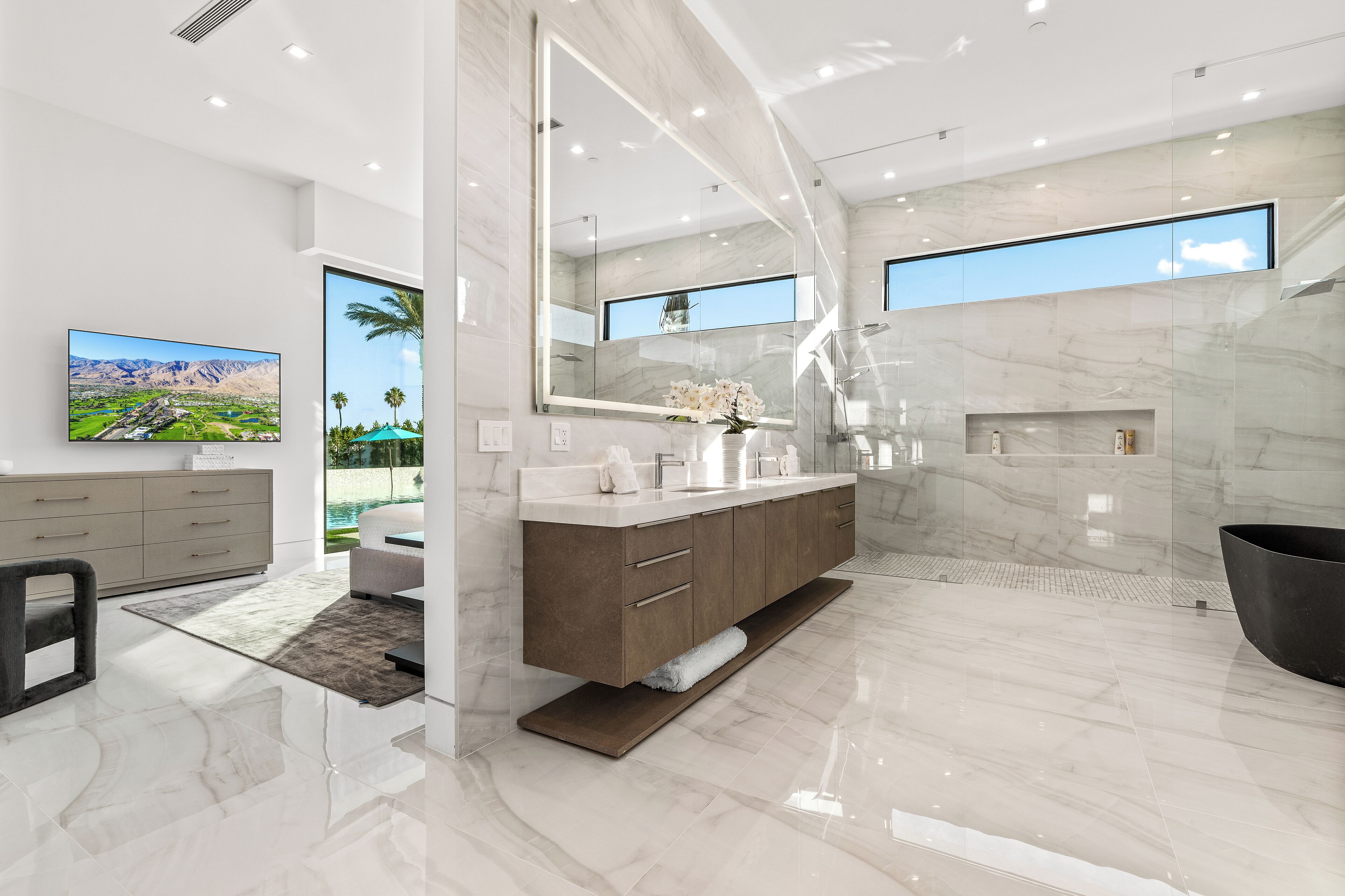 A modern bathroom with a large mirror, marble flooring, and a bathtub.