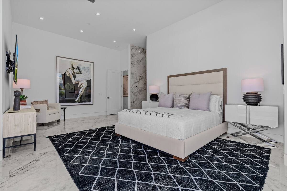 Een moderne slaapkamer met een groot bed, een marmeren vloer en een zwart-wit tapijt.