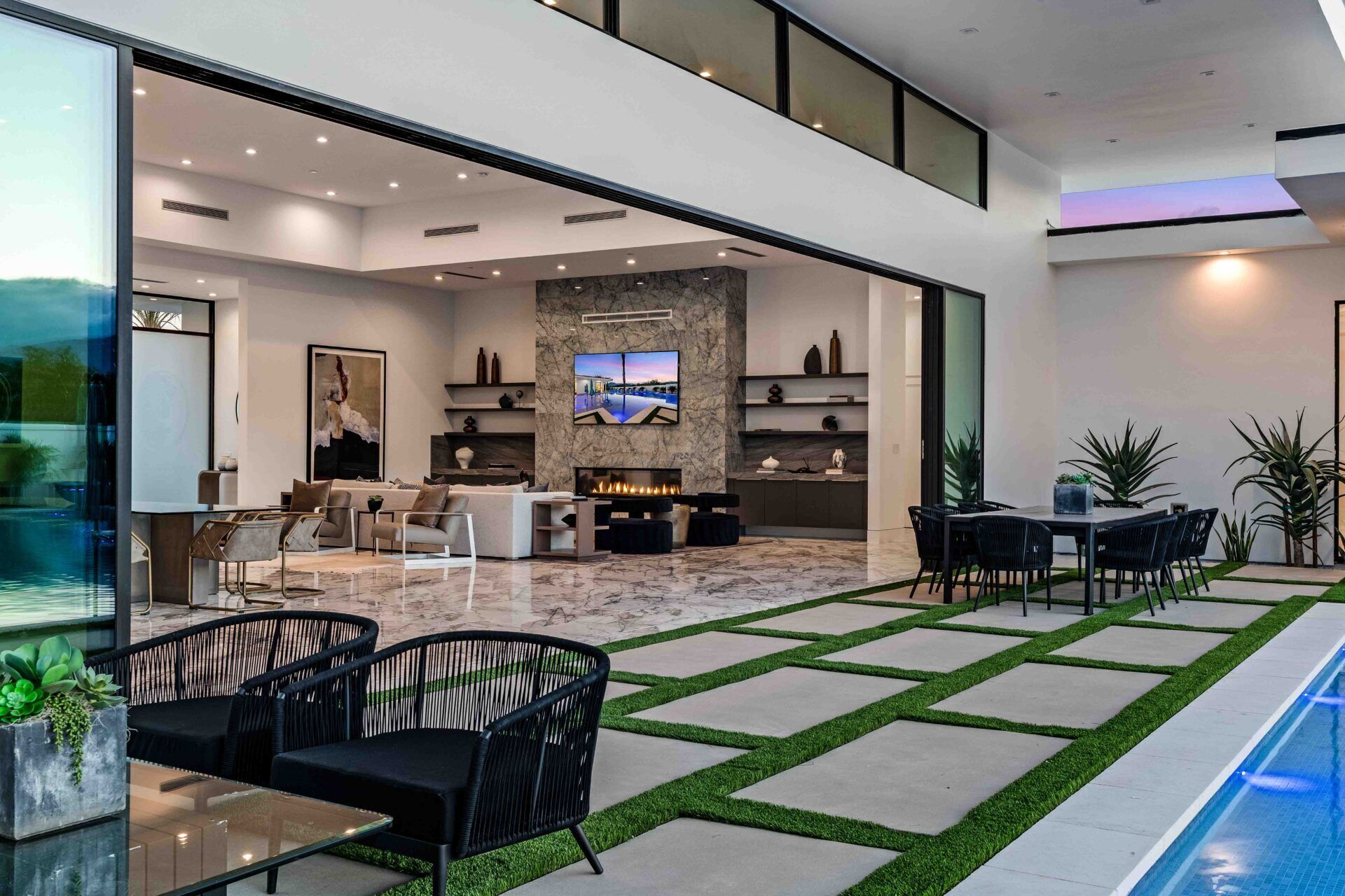 A modern living room with a fireplace, a TV, and a pool area with outdoor seating.
