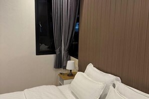 A hotel room with a bed, a nightstand with a lamp, and a window with curtains.