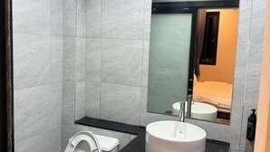 A modern bathroom with a white toilet, a round sink, and a mirror above the sink. - Big Elephant Hotel (Yasothon)
