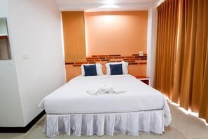 Una camera d'albergo con un letto grande, una testiera a motivi mattoncini, un comodino in legno e una finestra con tende.