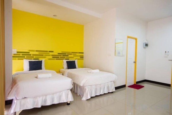A hotel room with two beds, a bright yellow accent wall, and a red mat at the door.