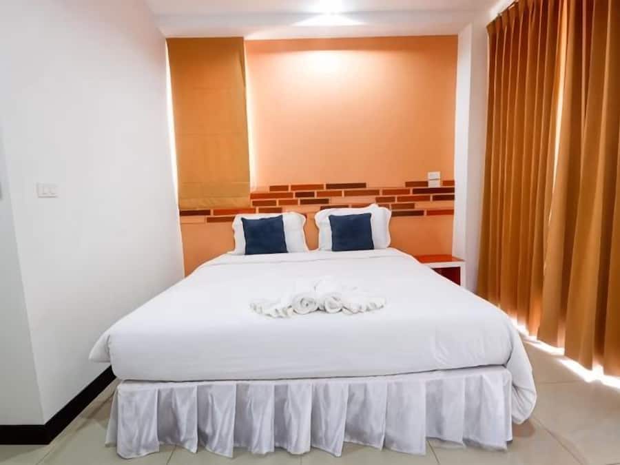A hotel room with a large bed, a headboard with a brick pattern, and a window with curtains.