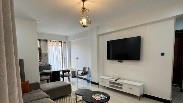 A modern living room with a grey sofa, a coffee table, and a flat-screen TV mounted on the wall.