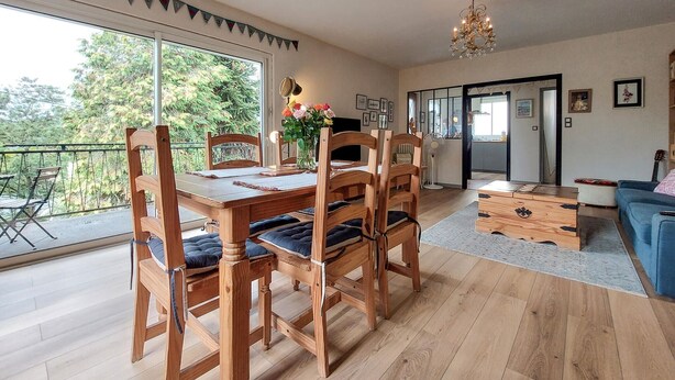 A dining area with a wooden table and chairs, a vase of flowers, and a view of greenery outside. - 3 bedroom nice apartment in Confolens (Confolens)