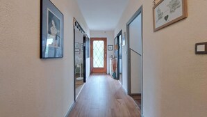 A hallway with wooden flooring, framed artwork on the walls, and a door leading to another room. - 3 bedroom nice apartment in Confolens (Confolens)