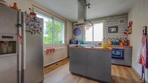 A kitchen with a central island, a refrigerator, a stove, and a window providing natural light. - 3 bedroom nice apartment in Confolens (Confolens)