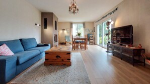A spacious living room with a blue sofa, a wooden coffee table, and a TV on a wooden stand. - 3 bedroom nice apartment in Confolens (Confolens)