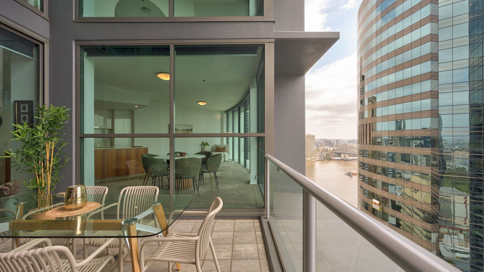 A modern building with large glass windows and a balcony with outdoor seating.