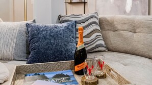 A cozy living room with a sofa, a tray with a bottle and glasses, and a bookshelf in the background. - The Luna Lodge - close to old Orchard beach (Saco)