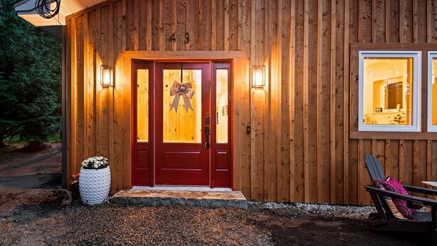 A wooden cabin with a red door, two windows, and a small porch area with a chair. - The Luna Lodge - close to old Orchard beach (Saco)