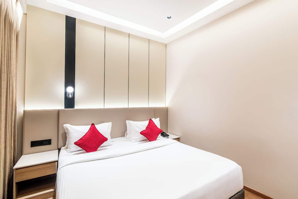 Ein Hotelzimmer mit einem großen Bett, zwei roten Kissen, einem Nachttisch und einem Beistelltisch.