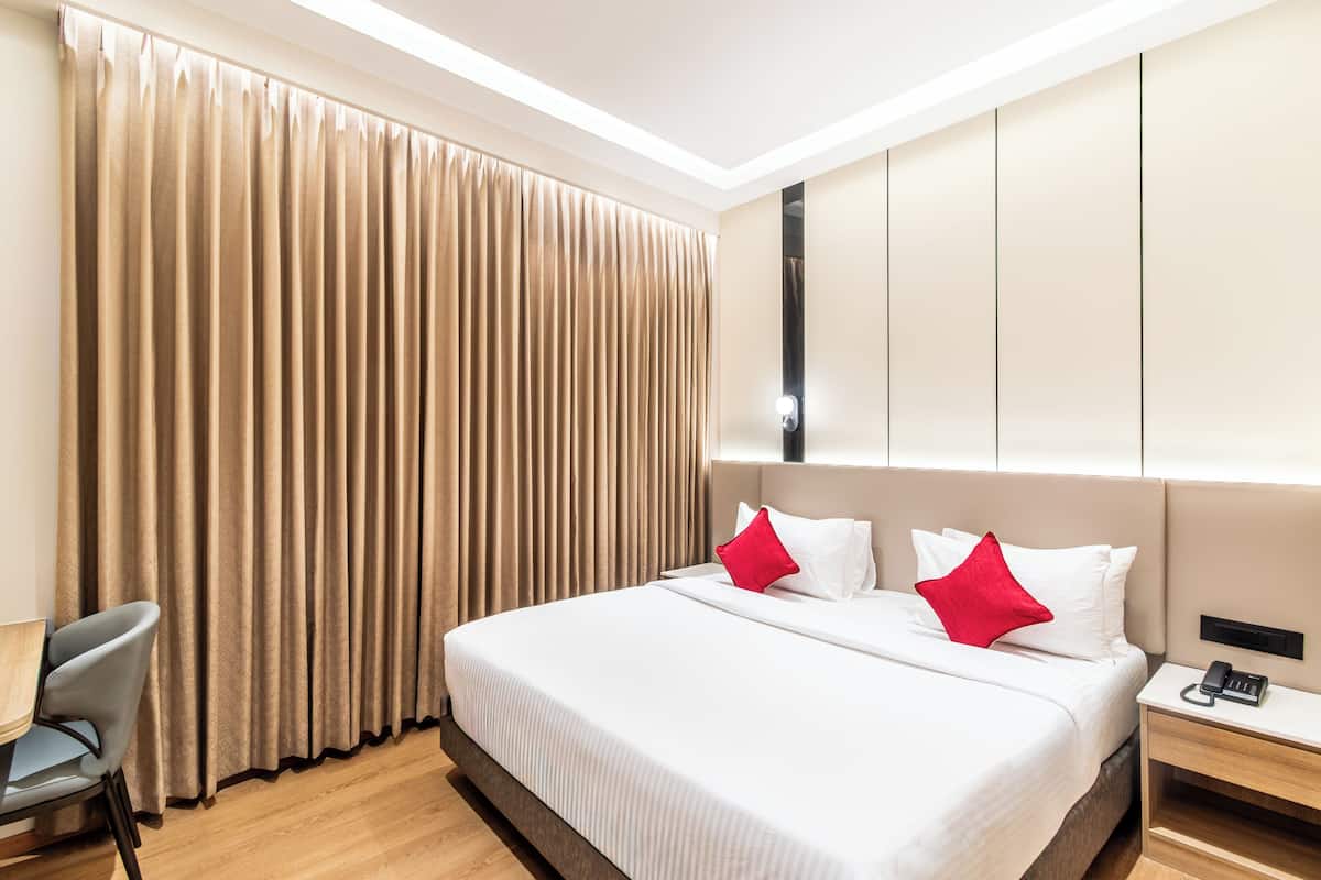 Ein Hotelzimmer mit einem großen Bett, einem Nachttisch mit Telefon und einem Sessel.