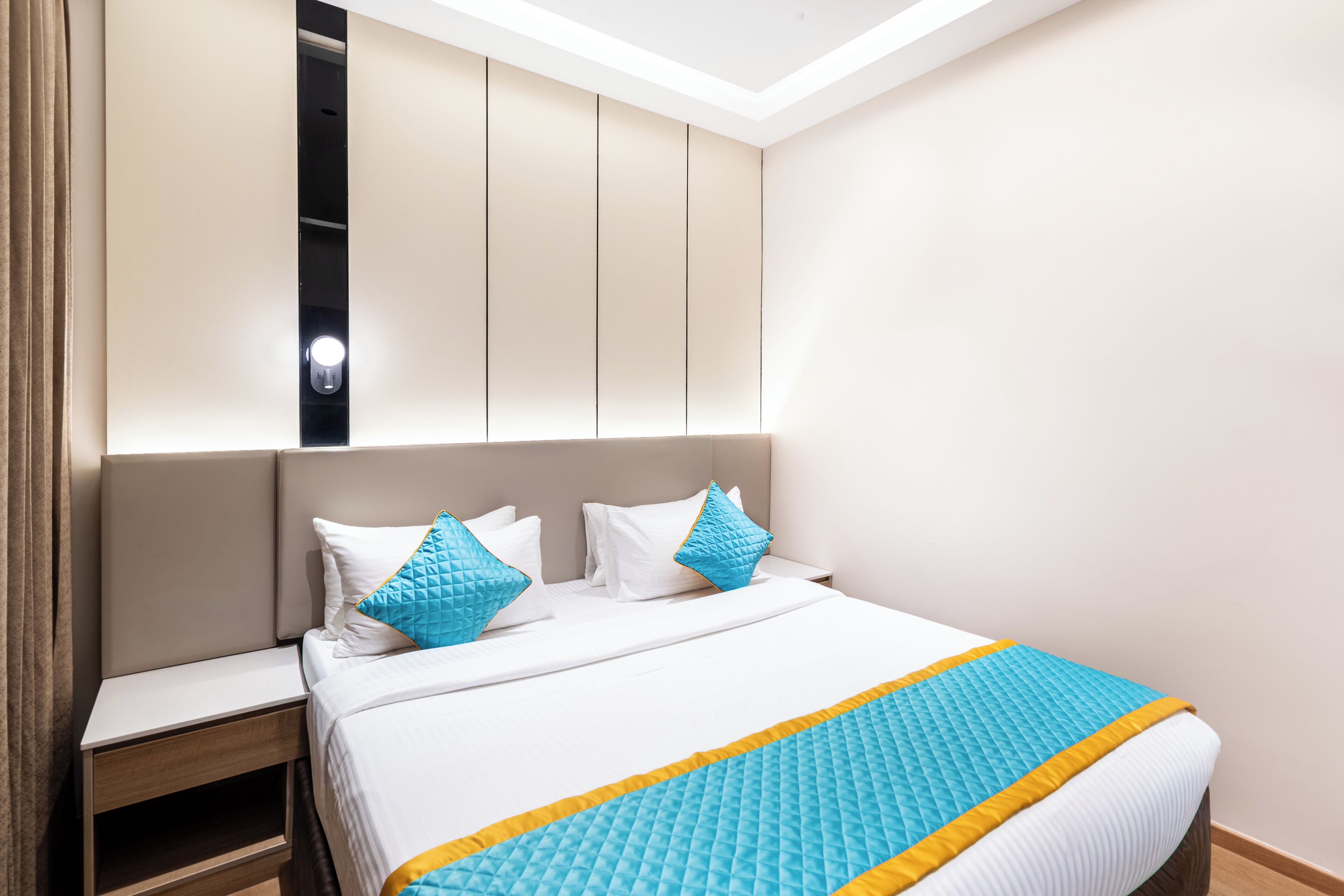 Una habitación de hotel con cama, mesita de noche y lámpara fijada en la pared.