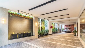 A hotel lobby with a brick floor, a reception desk, potted plants, and a car parked in the background. - Hotel Lenexa By Bestinn Leisure (Bengaluru)