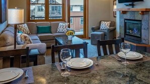 Una sala de estar acogedora con chimenea, un comedor con mesa dispuesta para dos personas y un rincón de estar confortable.