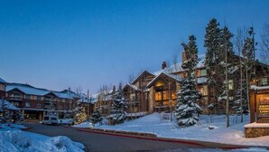Una cabaña con varias edificaciones, árboles cubiertos de nieve y un cielo despejado.