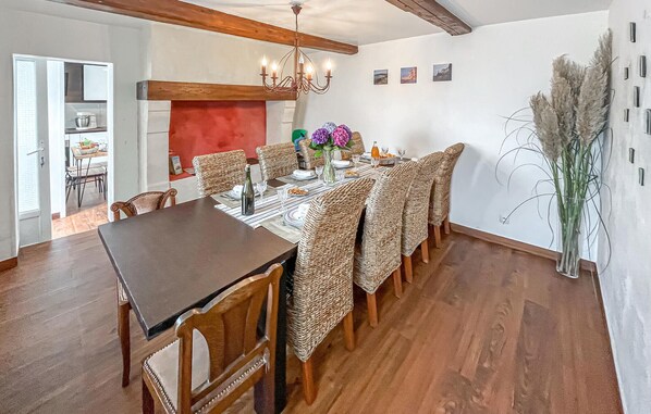 Comedor con mesa de madera, sillas de mimbre, candelabro y una pared de acento roja.