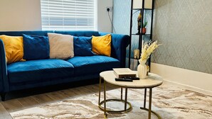 A living room with a blue sofa, a round coffee table, and a patterned rug.