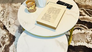A round table with a book titled 'PALM SPRINGS', a remote control, and a vase with dried plants.