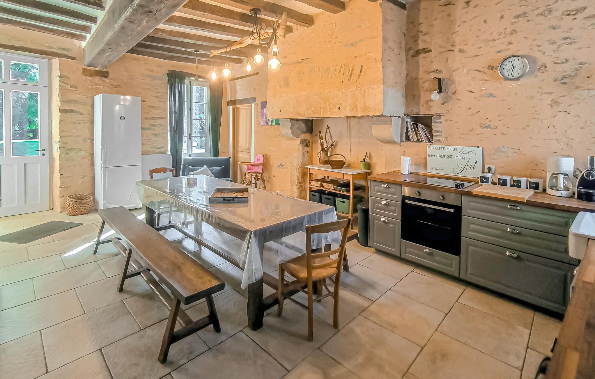 Una cocina rústica con una mesa de madera, un banco y paredes de piedra.