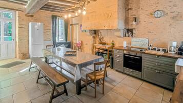 Una cocina rústica con una mesa de madera, un banco y paredes de piedra.