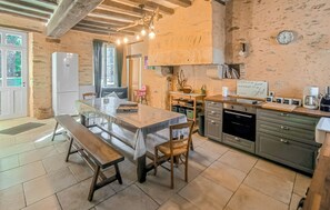 Una cocina rústica con una mesa de madera, un banco y paredes de piedra.