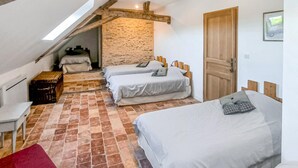 Ein Schlafzimmer mit zwei Betten, einer Holzbalkendecke, einer Steinwand und einer Tür.
