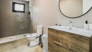 Een moderne badkamer met douche, toilet en wastafel.