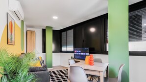 Een moderne kamer met een eettafel, stoelen, een computer en een plant.