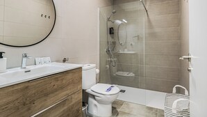 Ein modernes Badezimmer mit einem Holz-Waschtisch, einer Toilette, einer Duschkabine aus Glas und einem großen Spiegel.