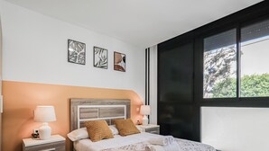 Ein Schlafzimmer mit einem Bett, zwei Nachttischen, einem Fenster und Wandbildern.
