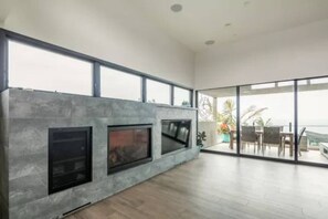 Uma sala de estar ampla com lareira, janelas grandes e vista para o exterior.